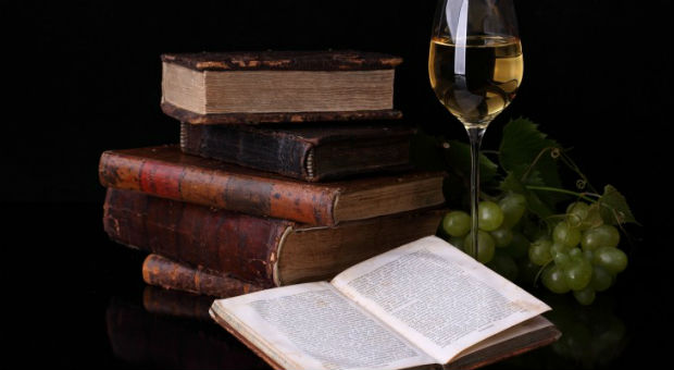 Old books glass of wine and grapes 730x400